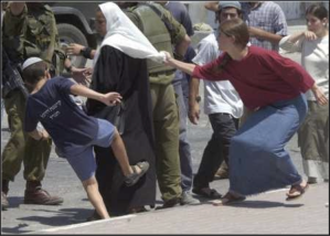 Settlers attacking a Palestinian woman while soldiers do nothing